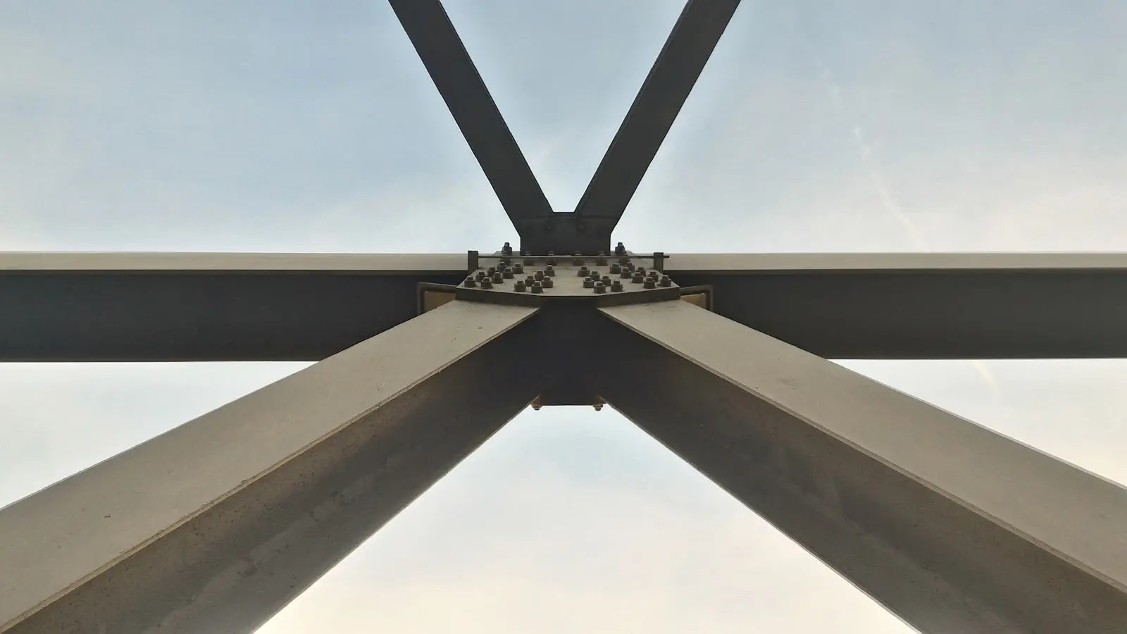 A bolted structural steel connection — flange plate, high-strength bolts torqued and marked, primer-red steel members meeting square.